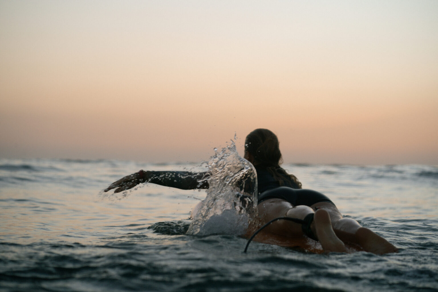 Girl paddling into the line up when the sun already set