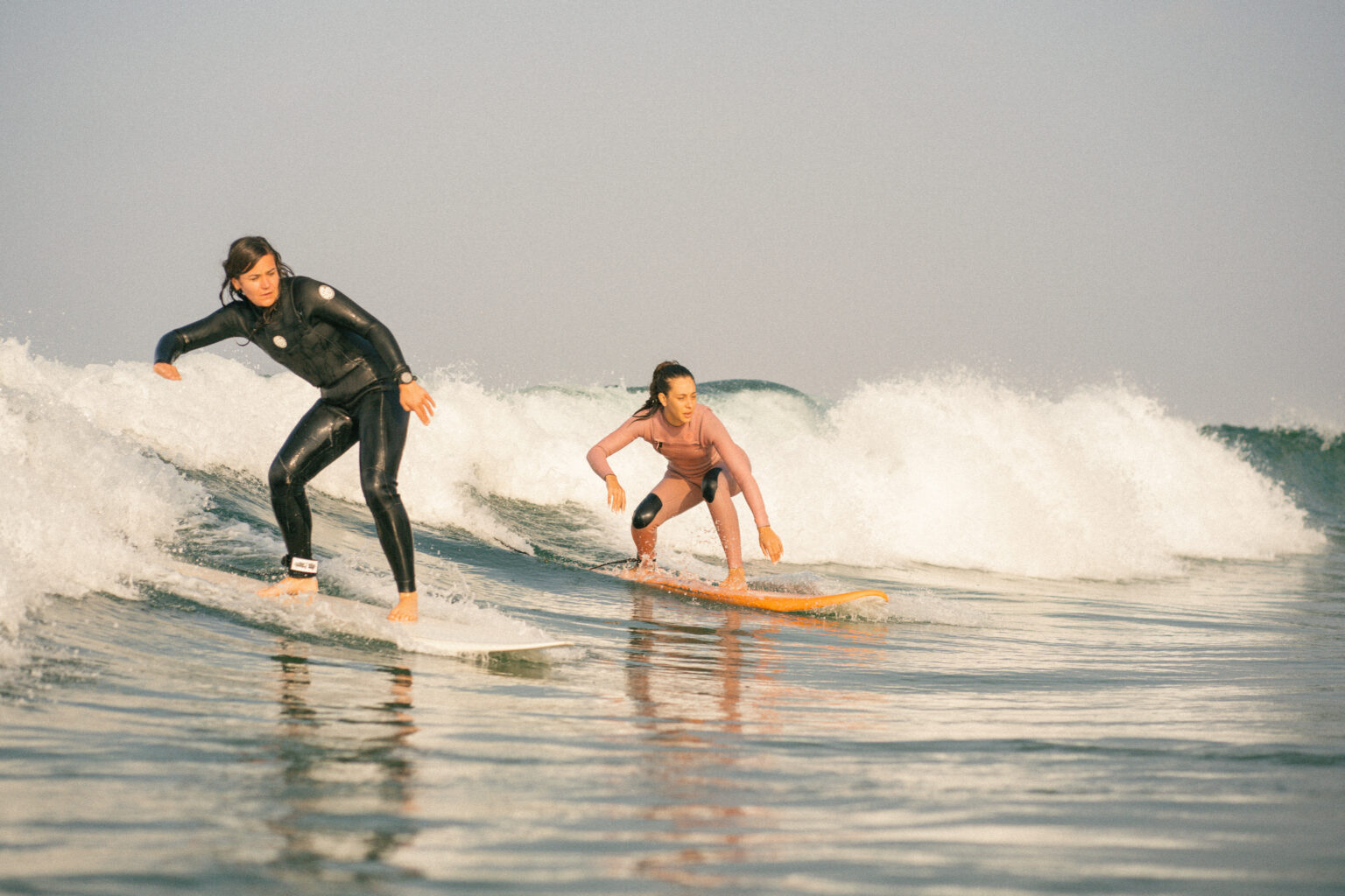 Two intermedtiate surfers catching a partywave together at anza beach, agadir