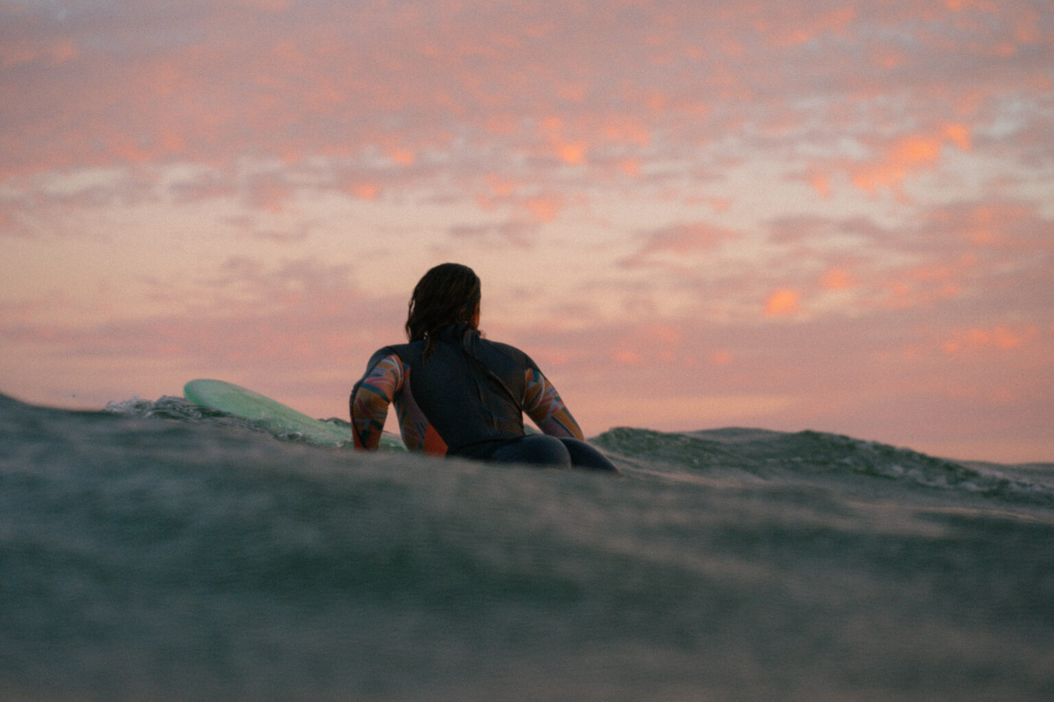Surfer paddling into the sunset at anza beach, agadir