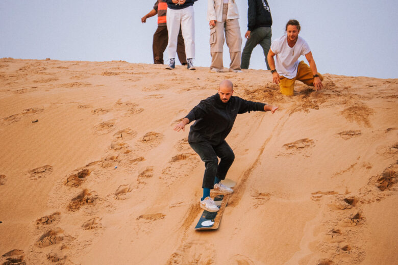 Man sandbaording down Tamri Sandunes, Agadir